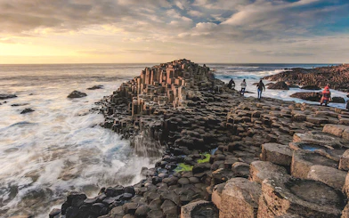 Giant's Causeway basalt columns with visitors exploring the coastal landscape in Northern Ireland.