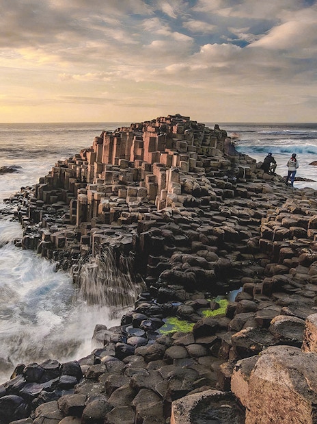 Giant's Causeway basalt columns with visitors exploring the coastal landscape in Northern Ireland.