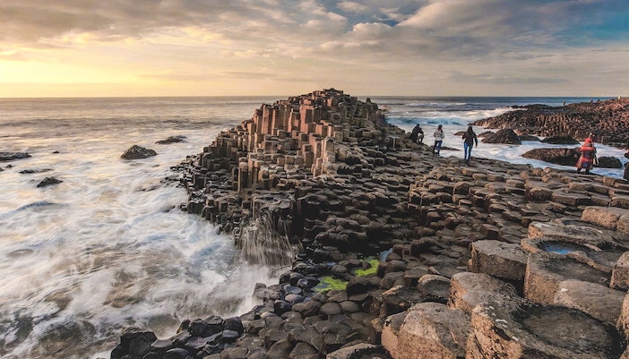 Giant's Causeway basalt columns with visitors exploring the coastal landscape in Northern Ireland.