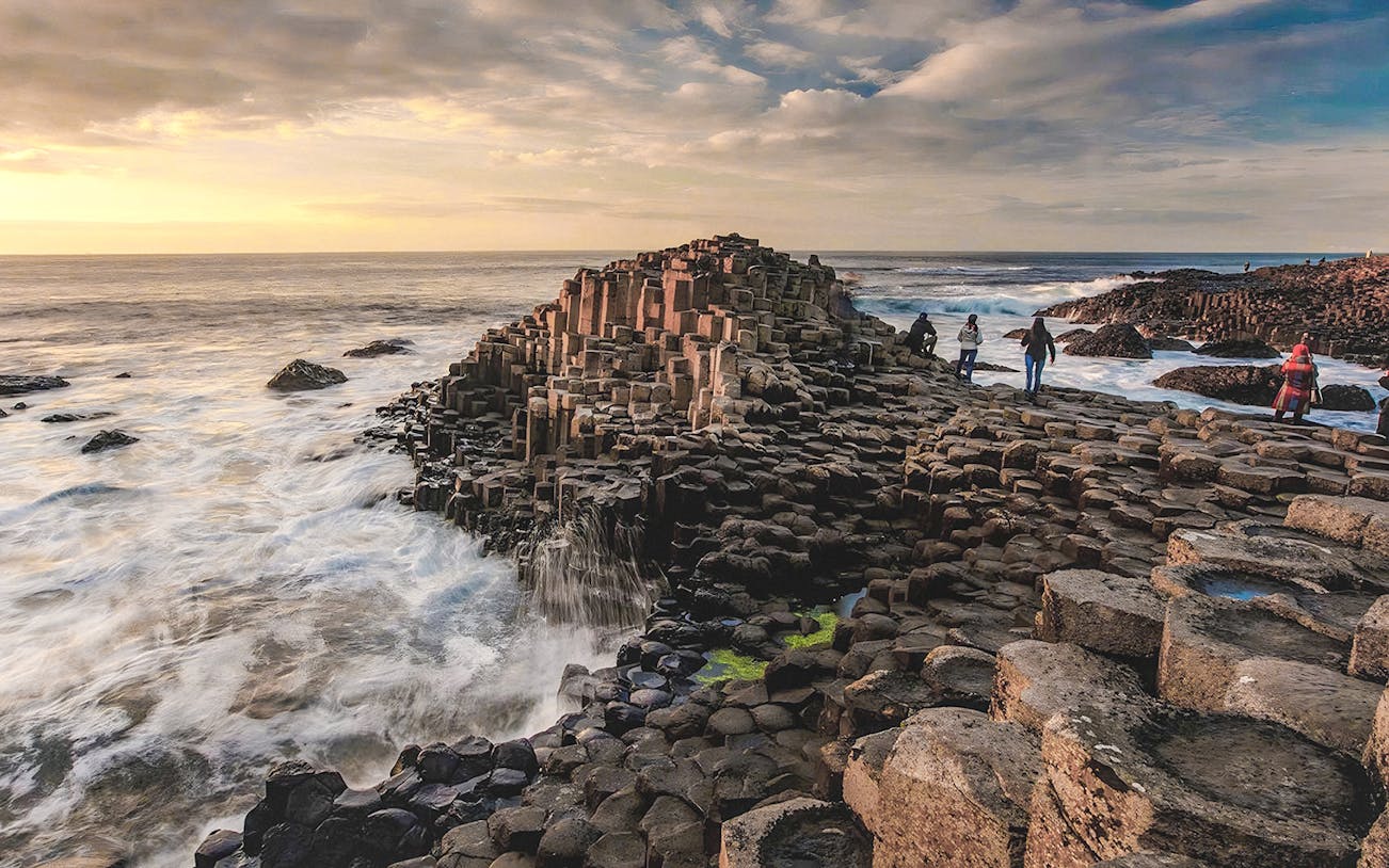 Giant's Causeway basalt columns with visitors exploring the coastal landscape in Northern Ireland.