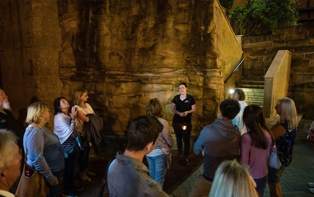 Group listening to a guide during Sydney True Crime Stories tour at night.