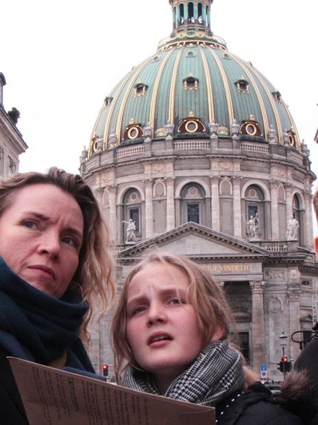 Mystery hunt participants at Amalienborg Palace, Copenhagen, pointing towards a landmark.