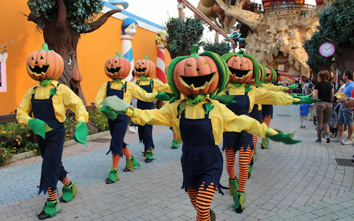 Pumpkin-headed performers in costume parade at Gardaland Halloween event.
