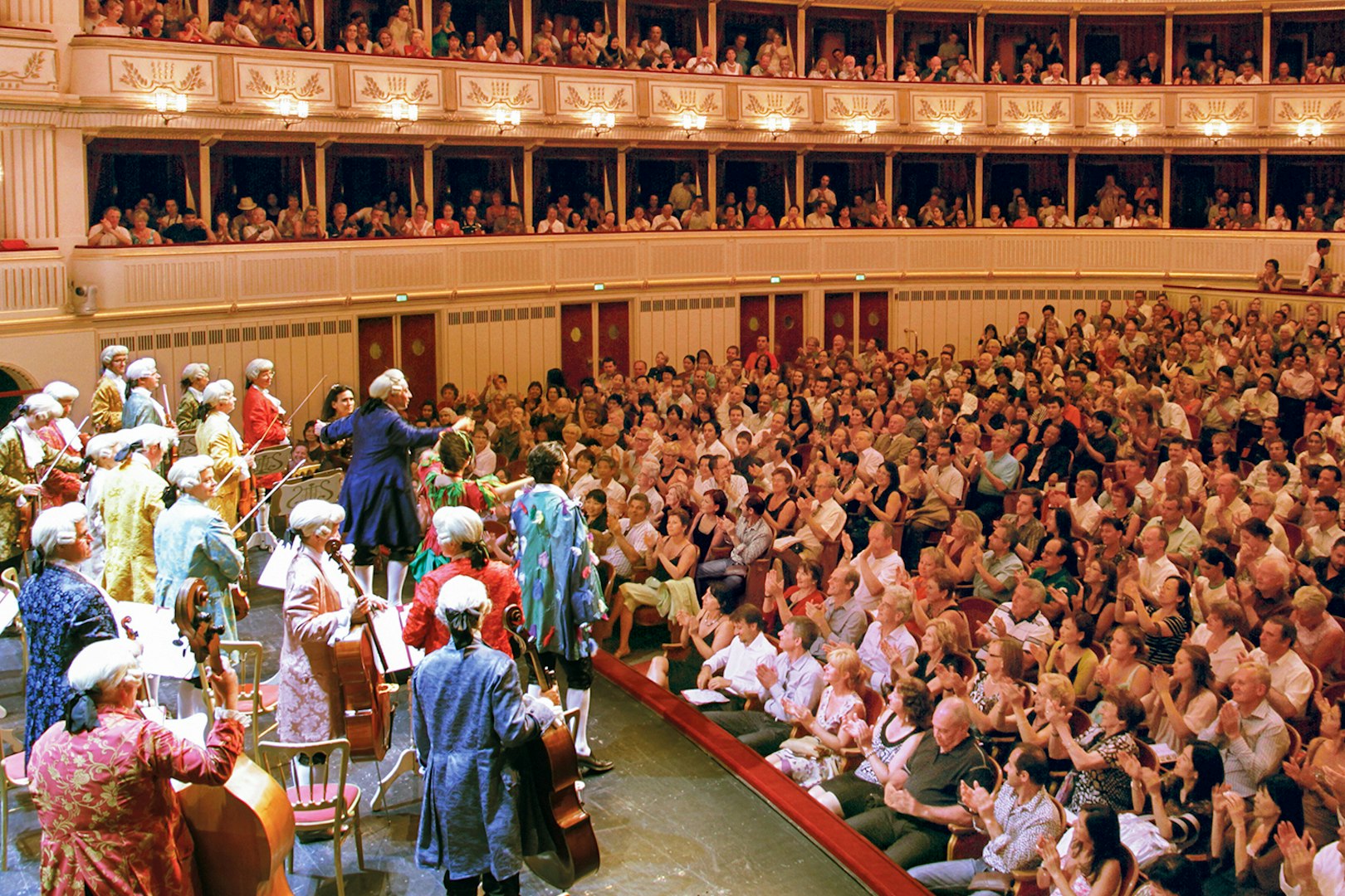 Orchestra performing Mozart at Vienna State Opera with audience applauding.
