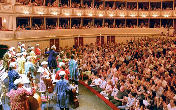 Orchestra performing Mozart at Vienna State Opera with audience applauding.