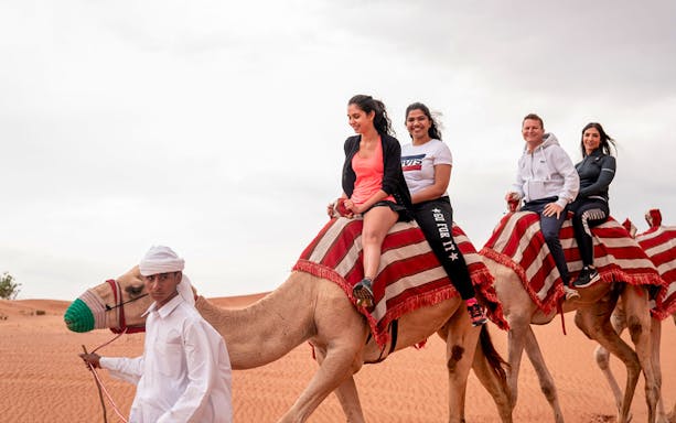 Tourists enjoying a camel ride during a desert safari.