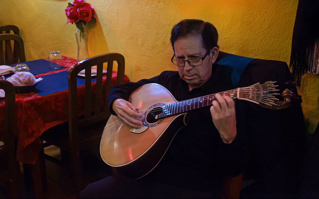 Musician playing Portuguese guitar during Alfama Fado tour in Lisbon restaurant.