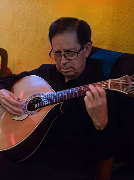 Musician playing Portuguese guitar during Alfama Fado tour in Lisbon restaurant.