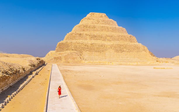 Person walking towards the Pyramid of Djoser in Giza, Egypt.