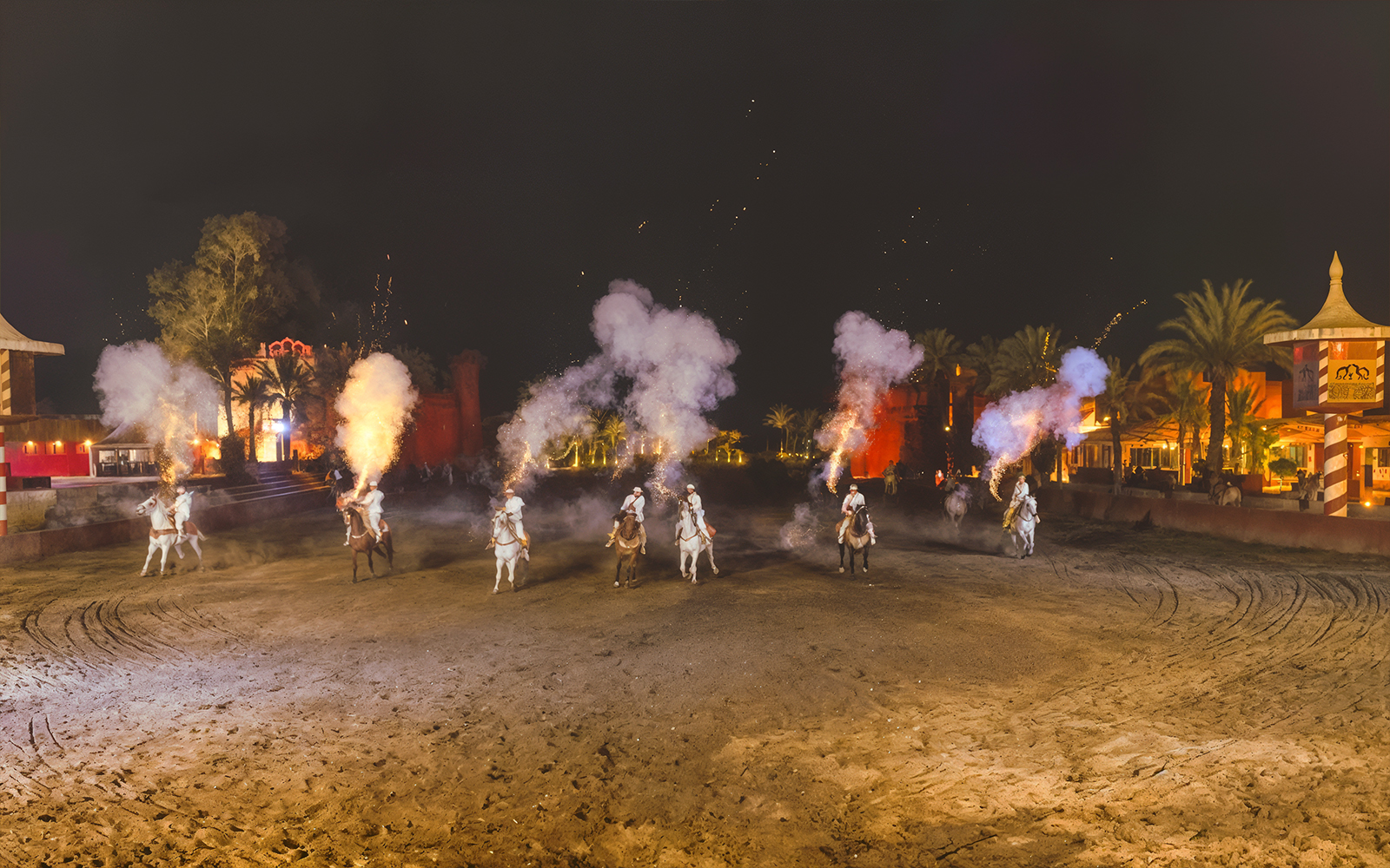 Riders on horses with smoke effects at Chez Ali Dinner & Fantasia Show, Morocco.