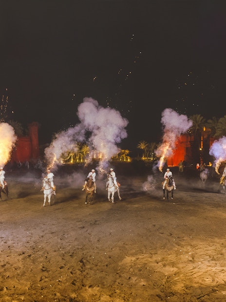 Riders on horses with smoke effects at Chez Ali Dinner & Fantasia Show, Morocco.
