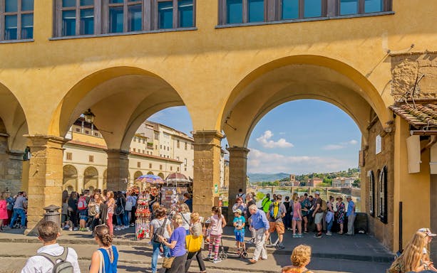 Tourists exploring shops on Ponte Vecchio near Vasari Corridor, Florence.