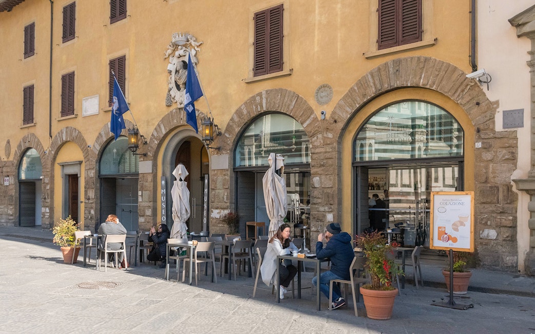 Facade of Opera del Duomo Museum with outdoor seating and visitors in Florence, Italy.