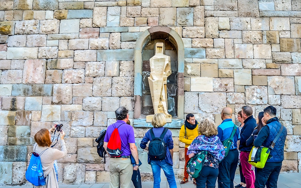Tour group observing a statue at Montserrat, Spain, during a half-day trip with rack-railway ride.