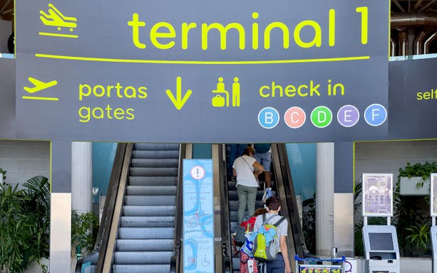 Faro Airport Terminal 1 entrance with passengers on escalator.