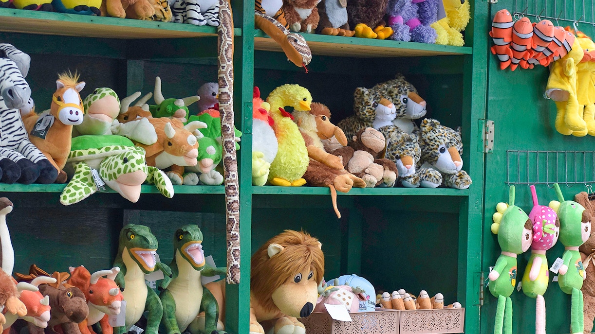 Stuffed animal toys displayed on shelves in a zoo shop.