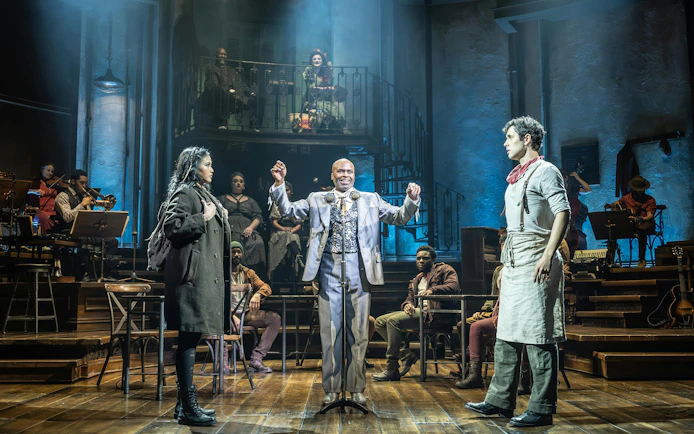 Stage performance of Hadestown in West End with actors and musicians on stage.