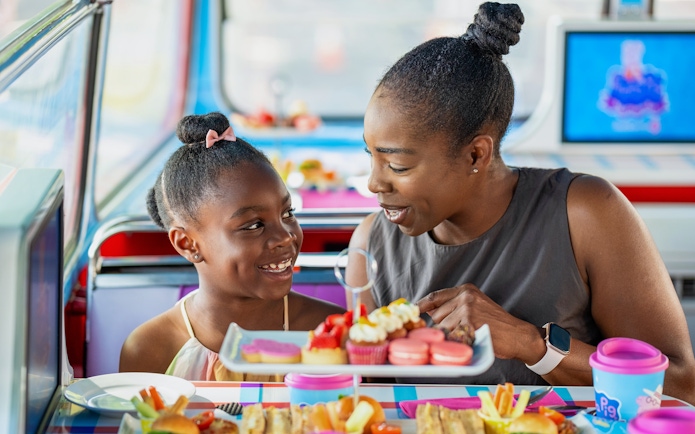 Guests enjoying treats on Peppa Pig themed bus tour for kids.