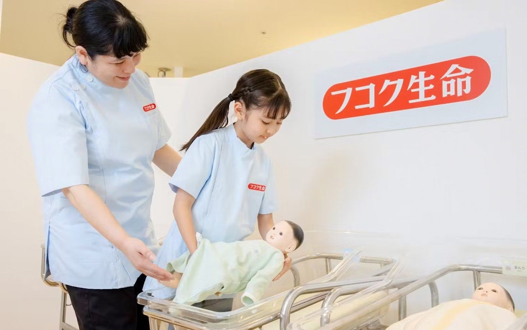 Child learning to care for a baby doll at KidZania Osaka Koshien.