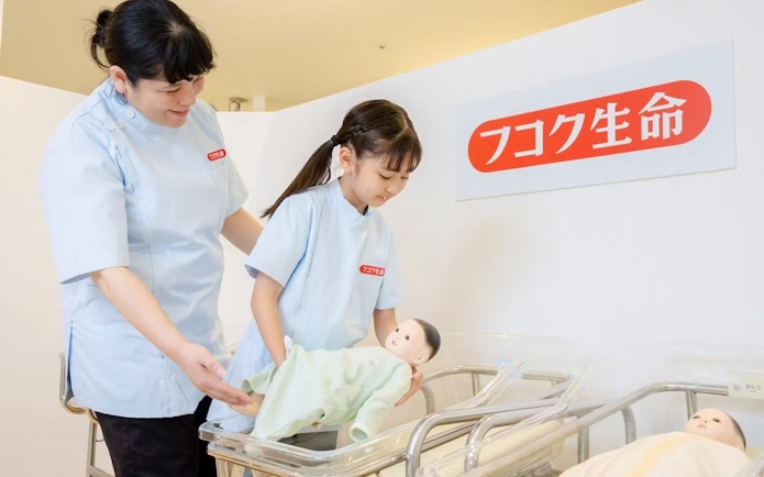 Child learning to care for a baby doll at KidZania Osaka Koshien.