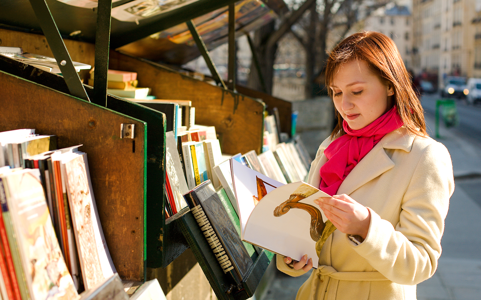 Person browsing books at Bouquinistes stalls along the Seine in Paris.