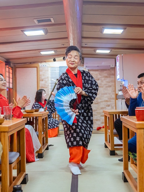 Guests enjoy a traditional Yakatabune hot pot dinner with a shamisen show in Japan.