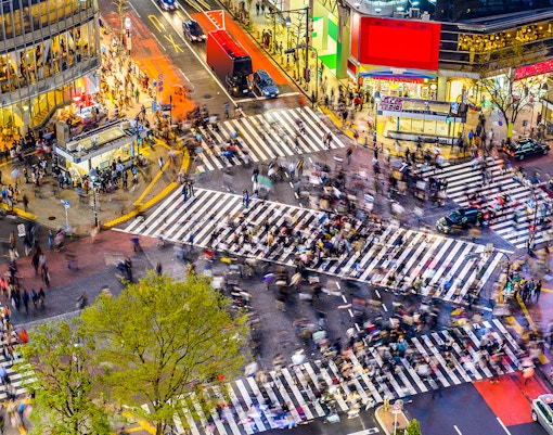 Crowds crossing Shibuya Crossing in Tokyo, Japan at night.