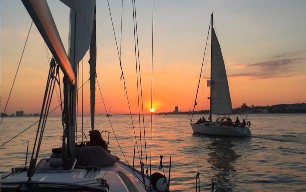Sailboats on Tagus River at sunset during Lisbon cruise.
