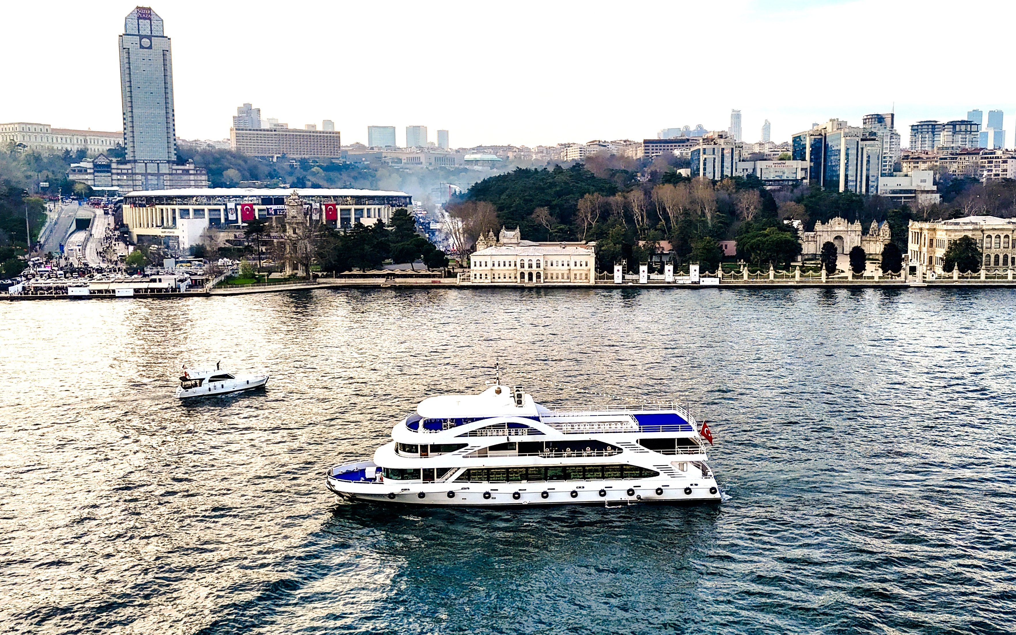 Bosphorus lunch cruise ship sailing near Istanbul's waterfront with cityscape in the background.