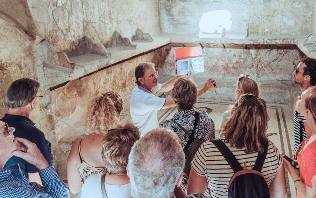 Group listening to archaeologist during Herculaneum tour inside ancient ruins.