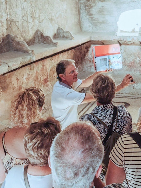 Group listening to archaeologist during Herculaneum tour inside ancient ruins.