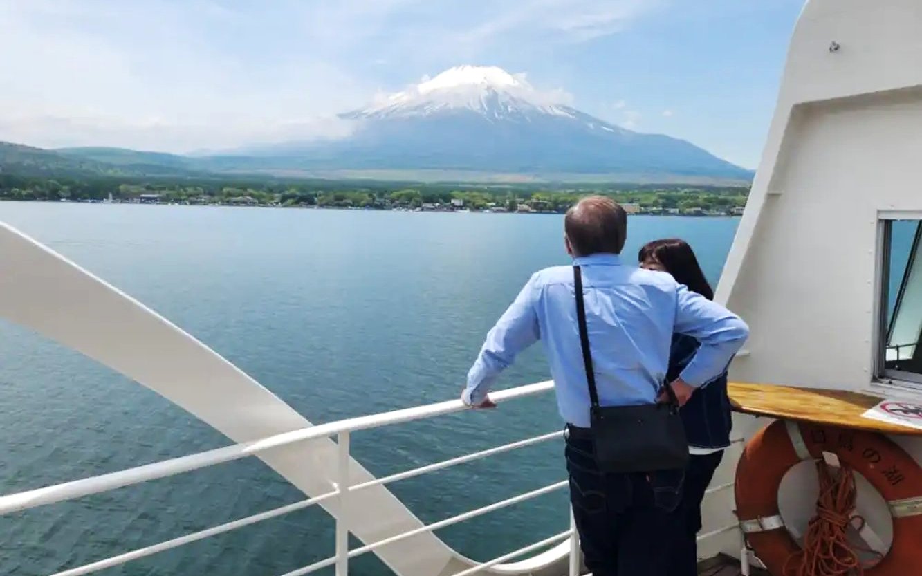 Tourists on Yamanakako Swan Lake boat with Mount Fuji view.