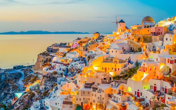 Oia village at sunset with iconic white buildings and windmills, Santorini, Greece.