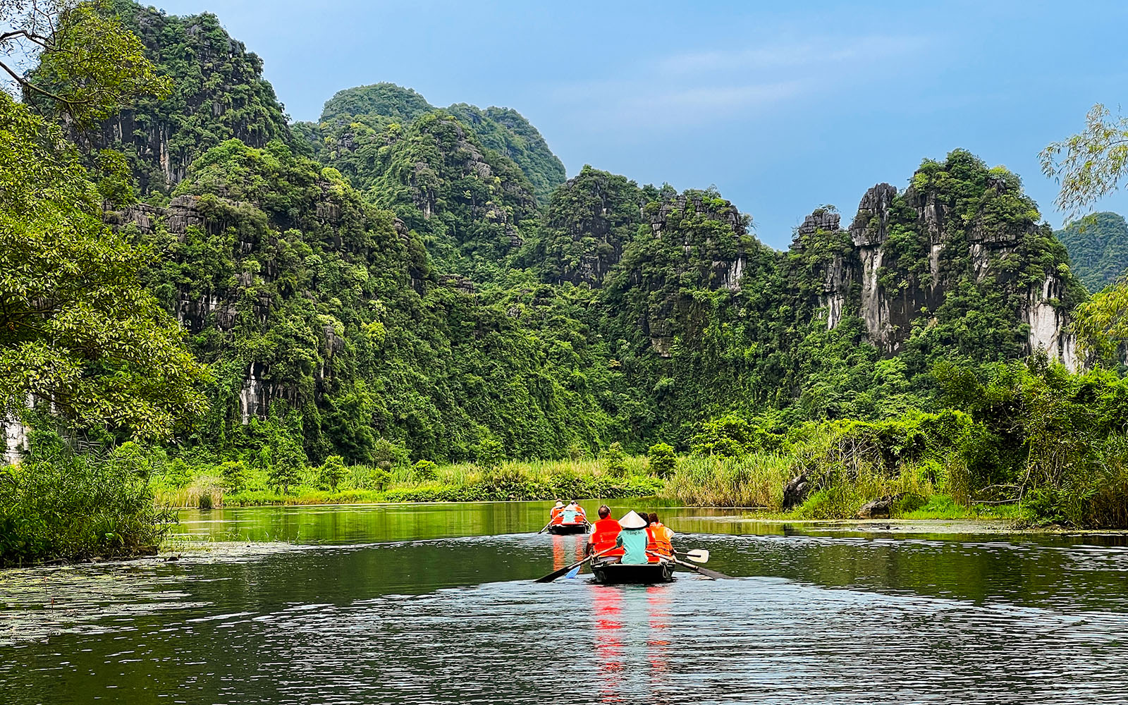 Boat tour through lush karst mountains in Trang An Landscape Complex, Ninh Binh, Vietnam.