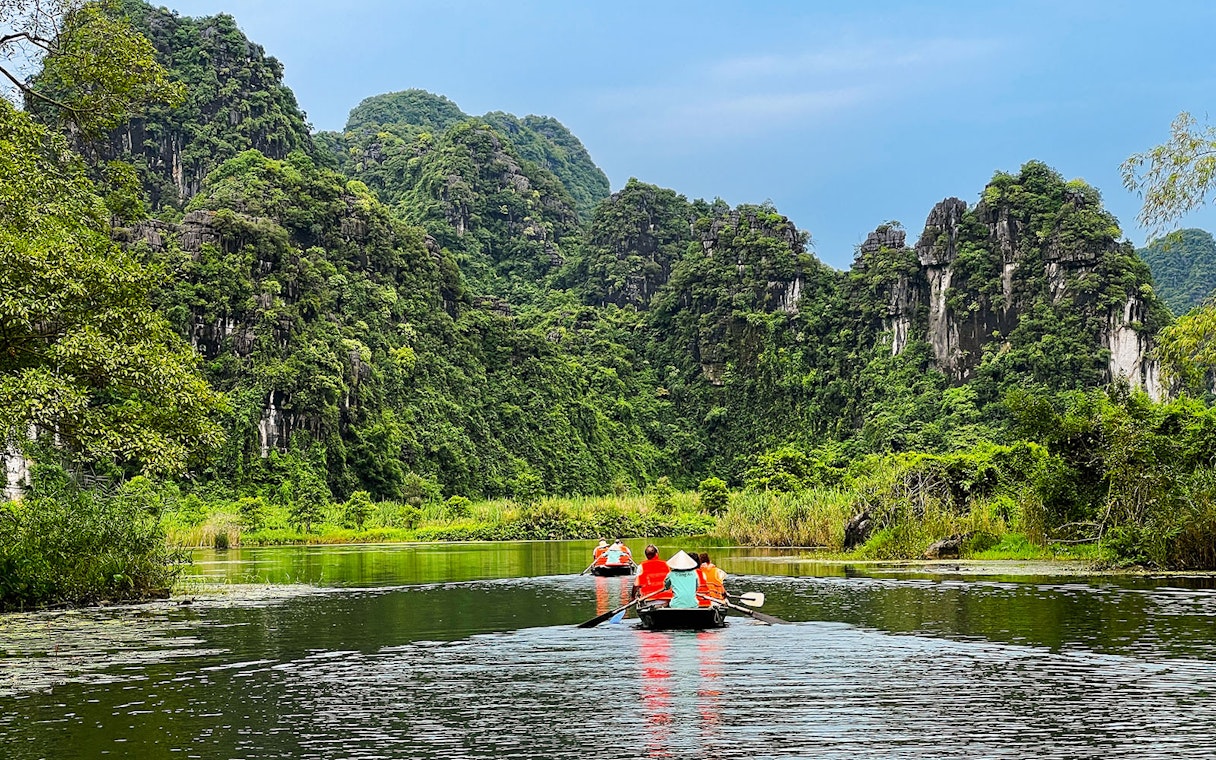 Boat tour through lush karst mountains in Trang An Landscape Complex, Ninh Binh, Vietnam.