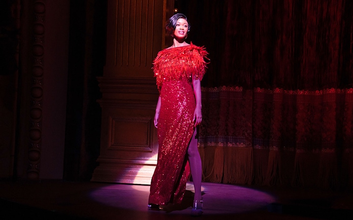 Performer in a red sequined dress on stage during a "Gypsy" musical scene.