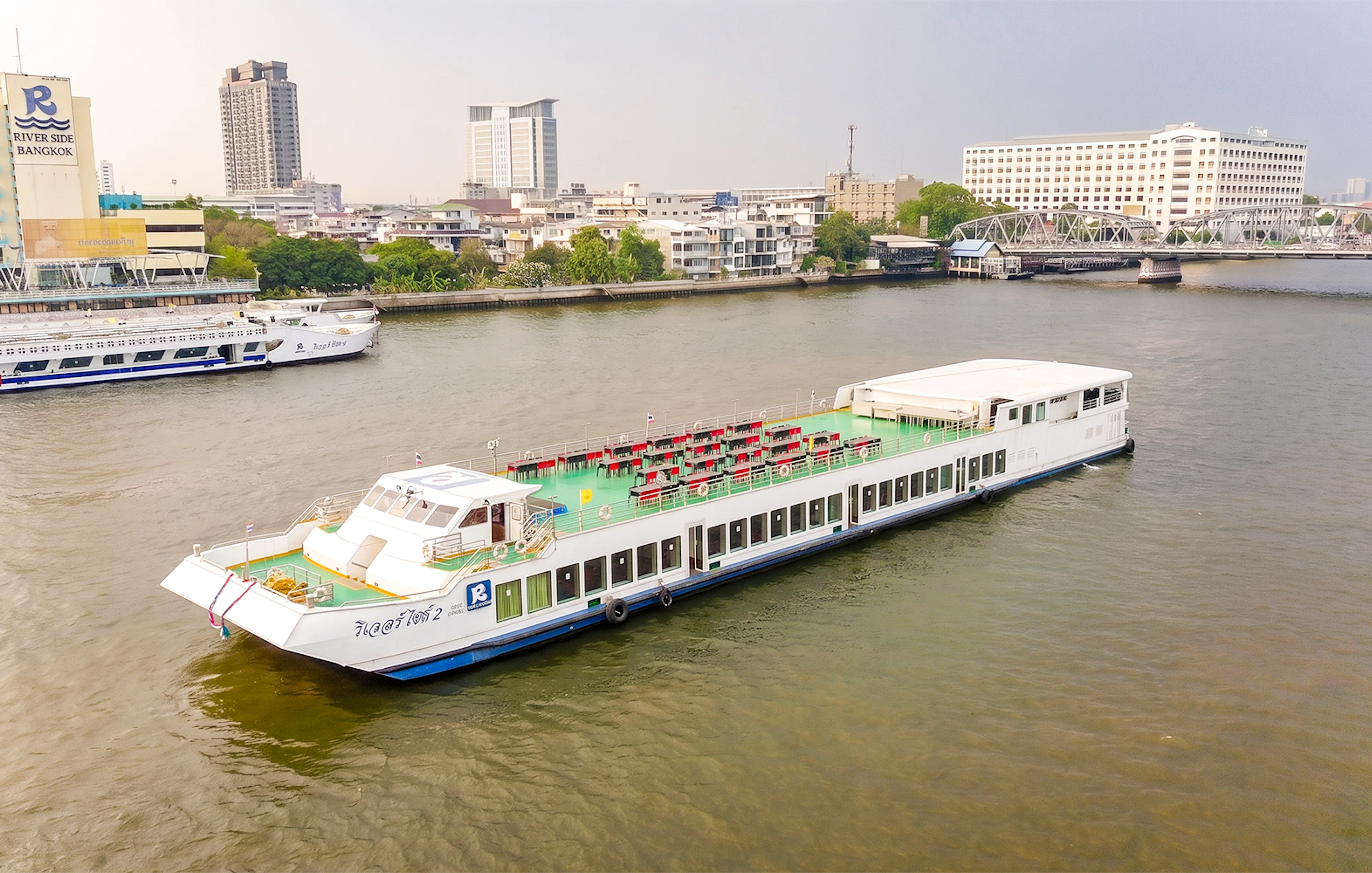 Riverside Faraya cruise boat on Chao Phraya River in Bangkok with cityscape background.