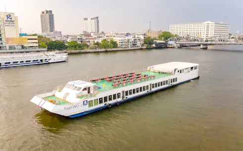 Riverside Faraya cruise boat on Chao Phraya River in Bangkok with cityscape background.