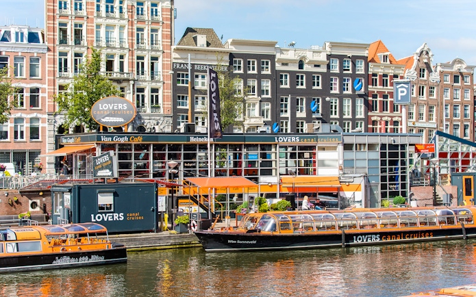 Lovers Canal Cruises docked in front of historic Amsterdam buildings, part of City Sightseeing Amsterdam.