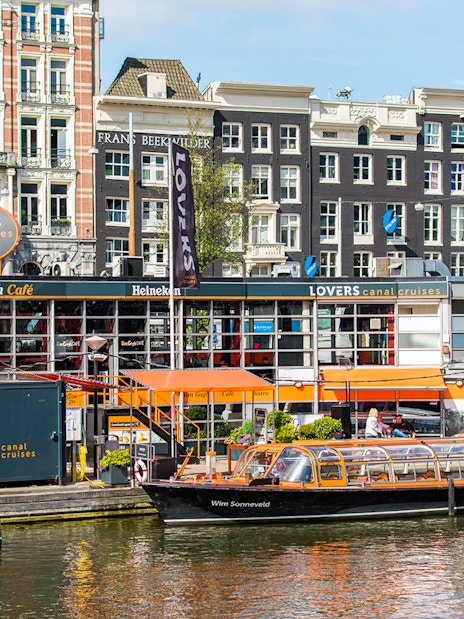 Lovers Canal Cruises docked in front of historic Amsterdam buildings, part of City Sightseeing Amsterdam.
