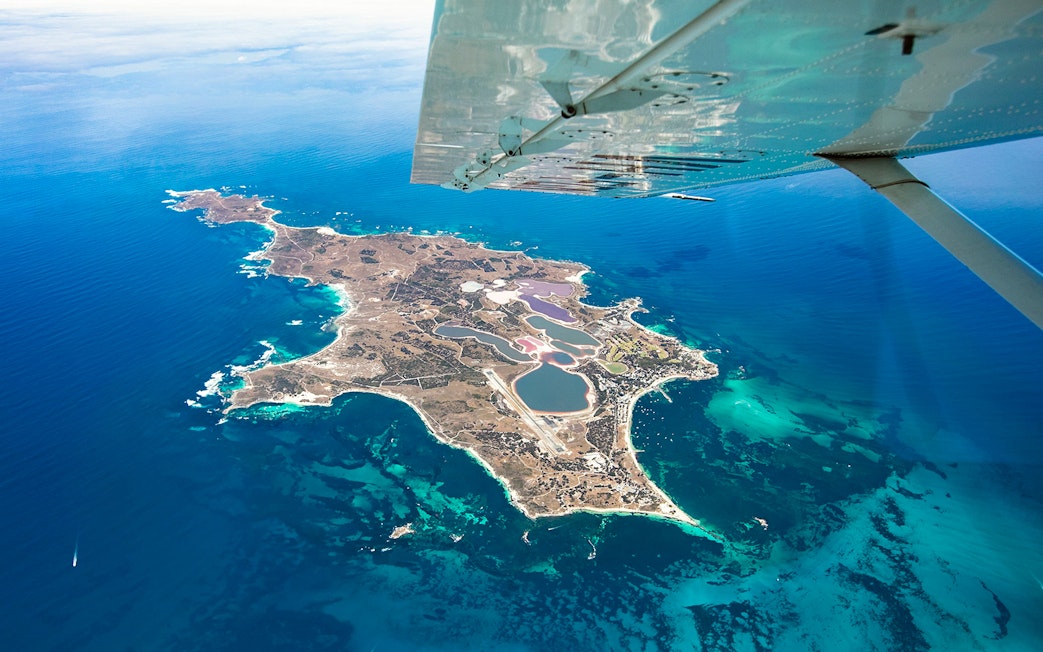 Aerial view of Rottnest Island from a plane, showcasing coastline and clear waters.