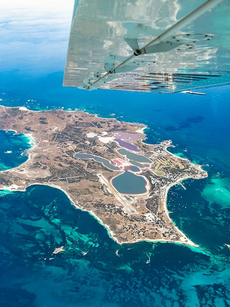 Aerial view of Rottnest Island from a plane, showcasing coastline and clear waters.