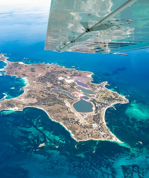 Aerial view of Rottnest Island from a plane, showcasing coastline and clear waters.
