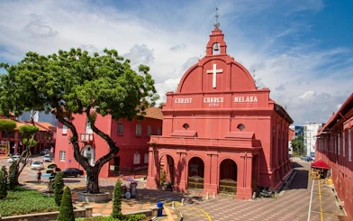 Christ Church in Malacca City, an 18th-century Anglican church with red facade and bell tower.