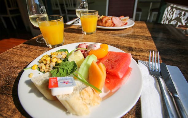 Plate of fresh fruit and bread with orange juice, part of Brisbane ballooning champagne breakfast.