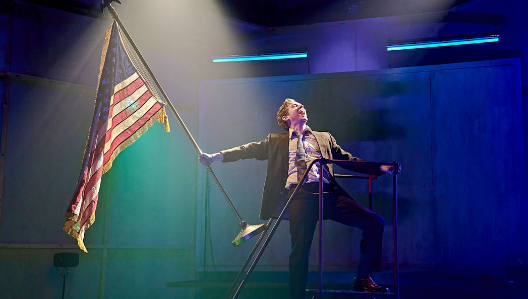 Performer on stage holding an American flag during Kenrex show.