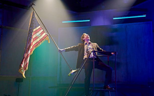 Performer on stage holding an American flag during Kenrex show.