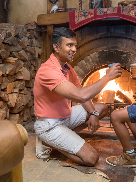 Father and son enjoying drinks by the fireplace at Hobbiton Movie Set, New Zealand.