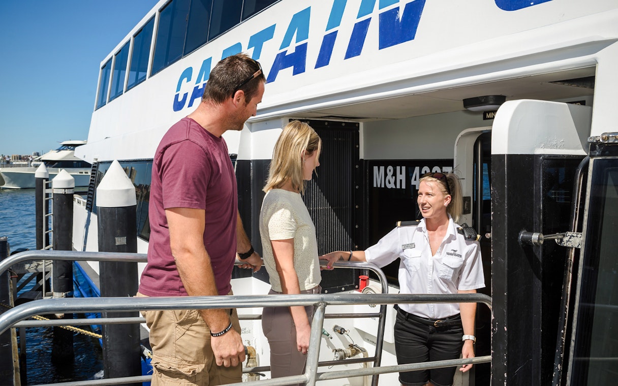 Captain Cook Cruises staff welcoming passengers aboard at the dock.