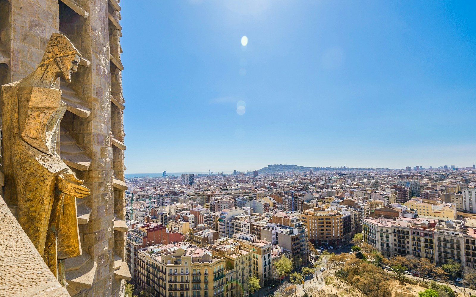View of Barcelona from Sagrada Familia tower with cityscape and statue.